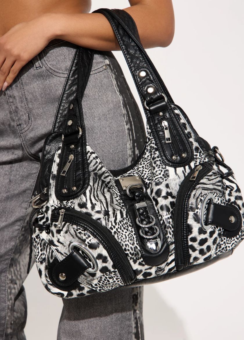 Person holding a leopard print handbag with zippers